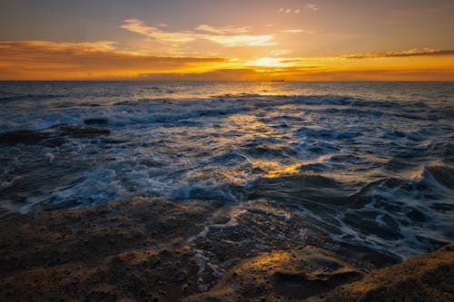 A sunset over the ocean with waves crashing