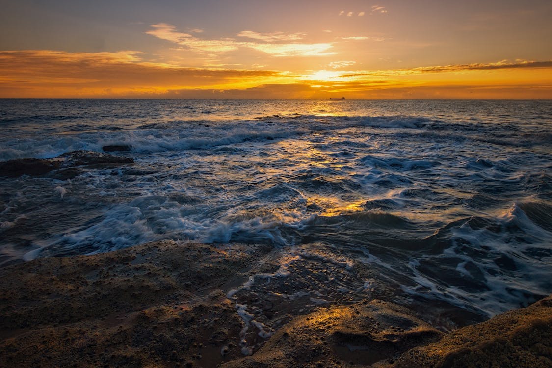 A sunset over the ocean with waves crashing