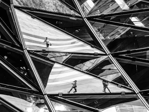 Black and white photograph of people walking through a glass building