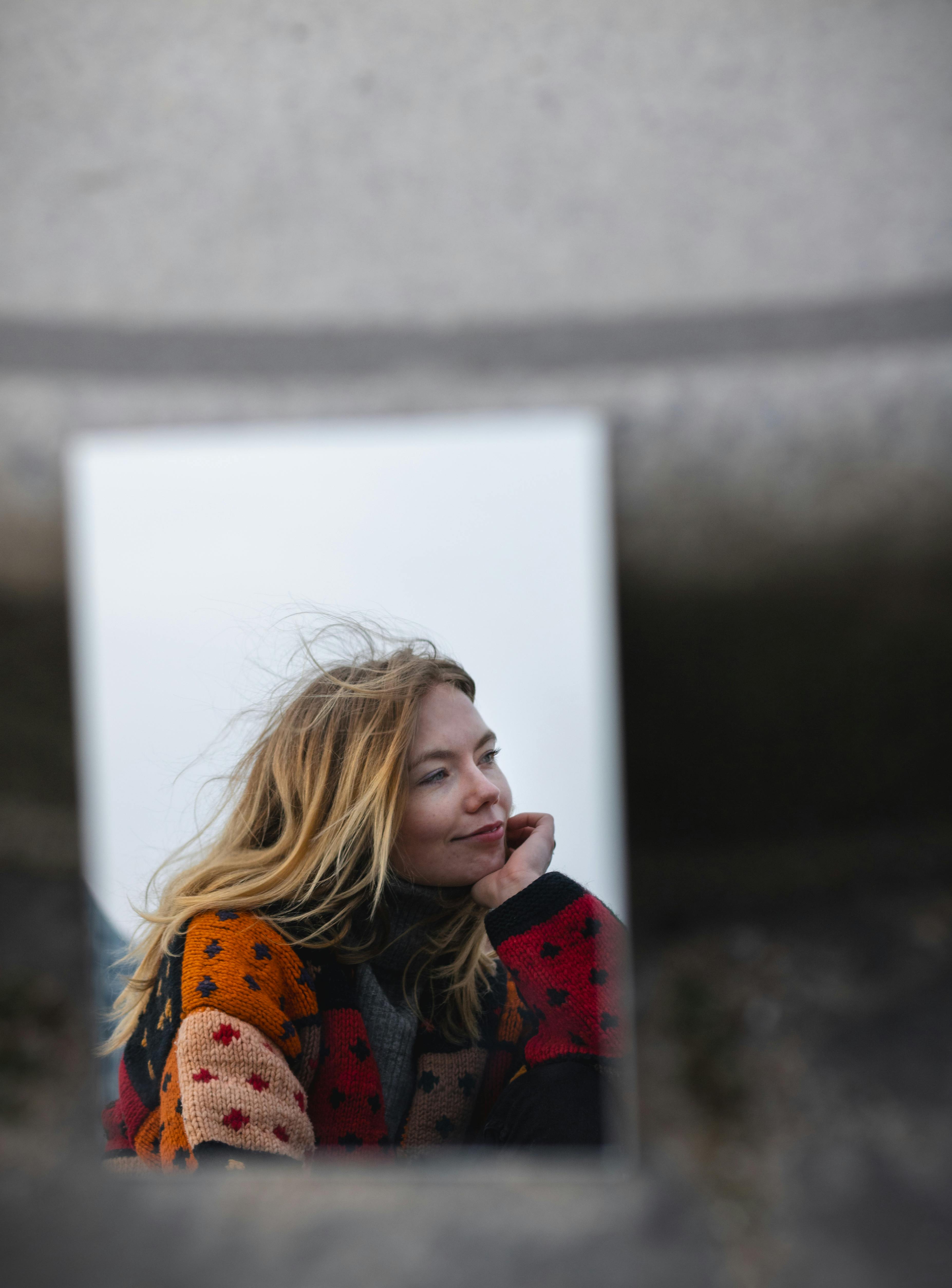 A woman smiling in a mirror reflection set in urban Hamburg, captured in fall. Vibrant and artistic.