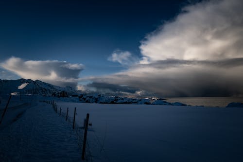 A snowy landscape with a fence and a mountain in the background