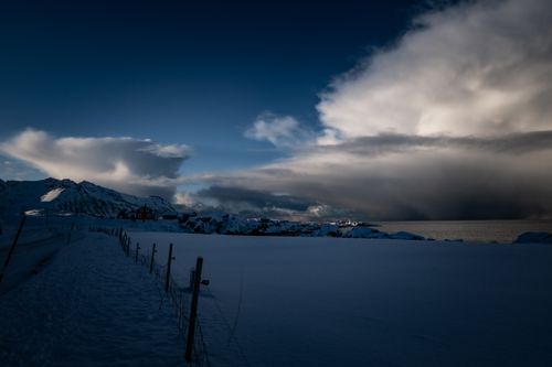 Free Spectacular snow-covered mountains at twilight with dramatic clouds over the sea. Stock Photo