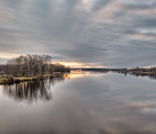 Free Tranquil view of a river reflecting the sunset sky, surrounded by trees in Wabasha, MN. Stock Photo