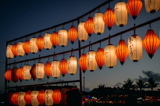 Beautiful display of orange and white lanterns hanging outdoors during a twilight festival.