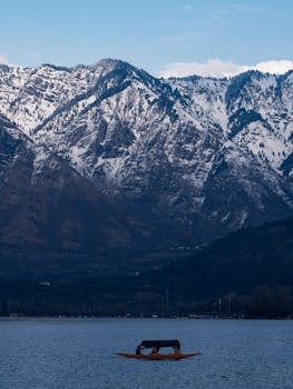 A tranquil lake with a boat framed by majestic snow-covered mountains.