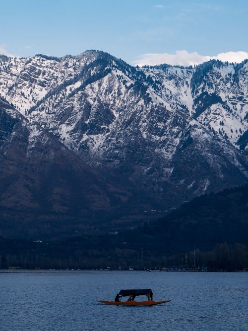 Free A tranquil lake with a boat framed by majestic snow-covered mountains. Stock Photo