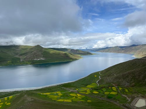 A lake surrounded by green grass and mountains