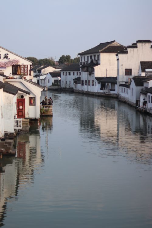 Free Charming canal lined with traditional white houses reflecting in the water. Stock Photo