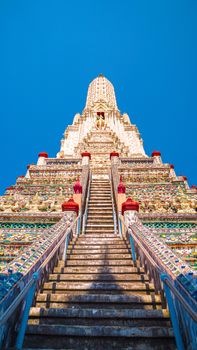 Vertical view of the ornate Wat Arun Temple staircase in Bangkok, capturing intricate details under a clear blue sky.