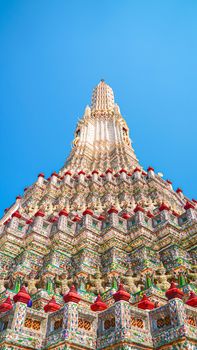 A stunning view of Wat Arun temple's intricate design in Bangkok under a clear blue sky.