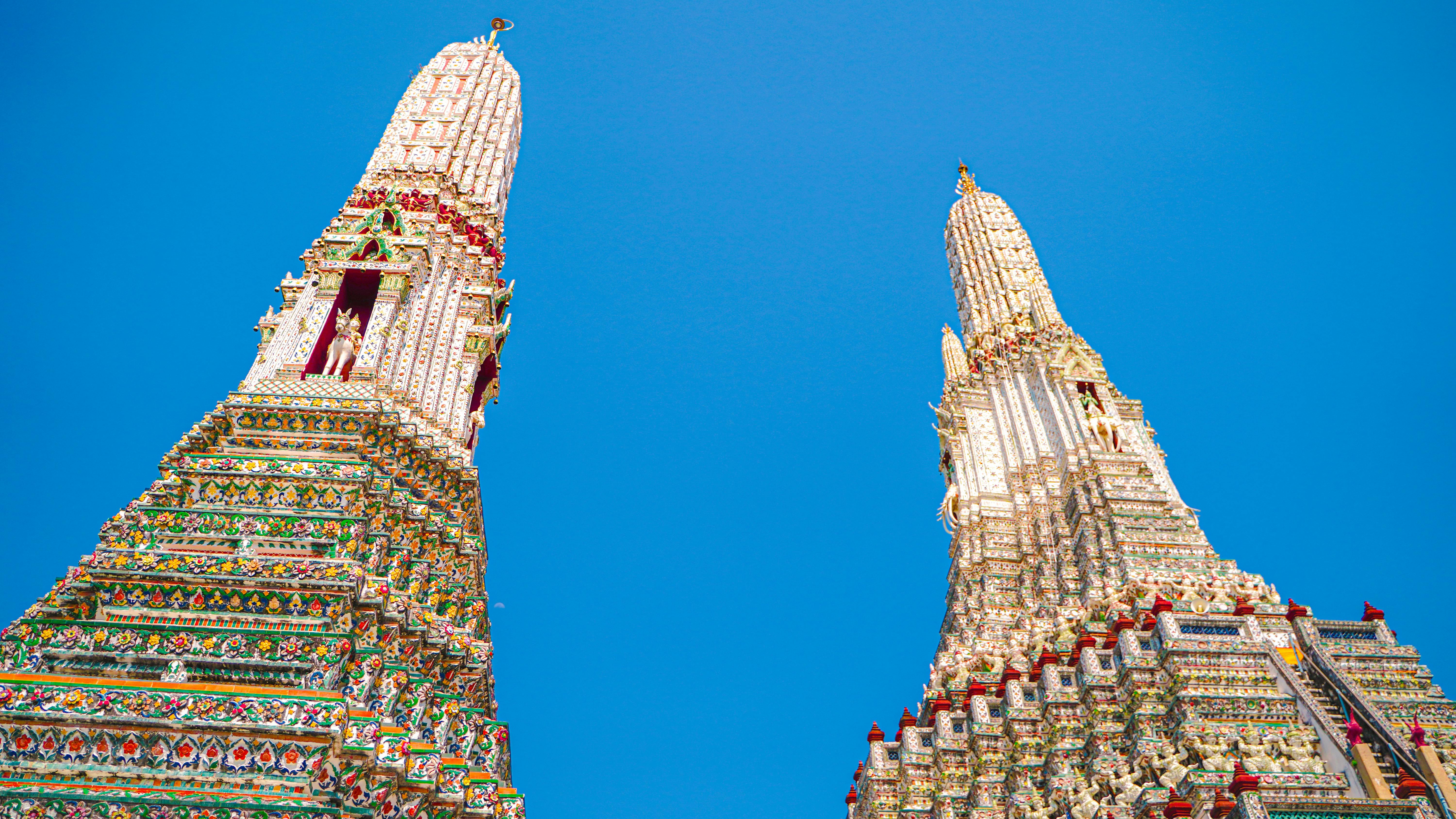 Low angle view of Wat Arun's ornate towers against a clear blue sky