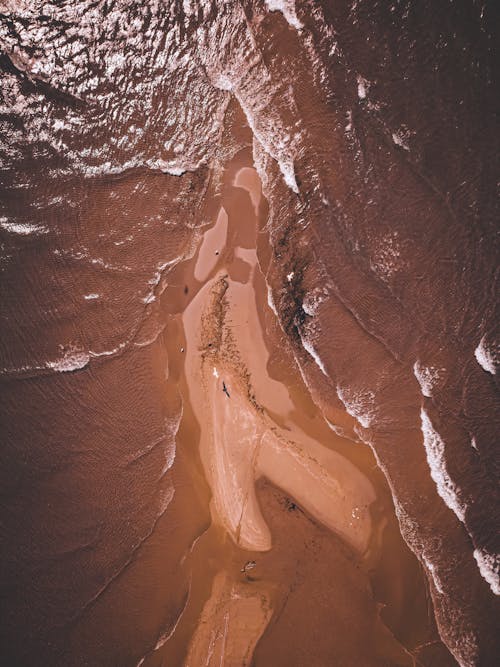Aerial Footage of a Brown Sandspit and Waves