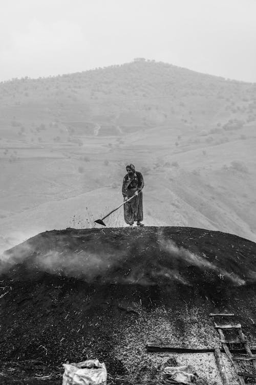 Woman Standing on Mound in Village and Working