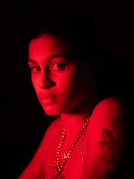 Artistic portrait of a young woman with red lighting creating a dramatic mood.