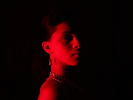 Striking portrait of a young woman illuminated by red light with a dramatic mood.