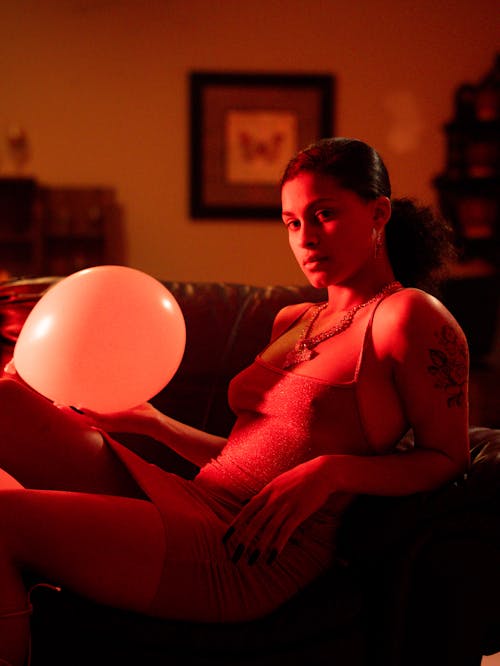 Fashion model sitting in red lighting in living room 