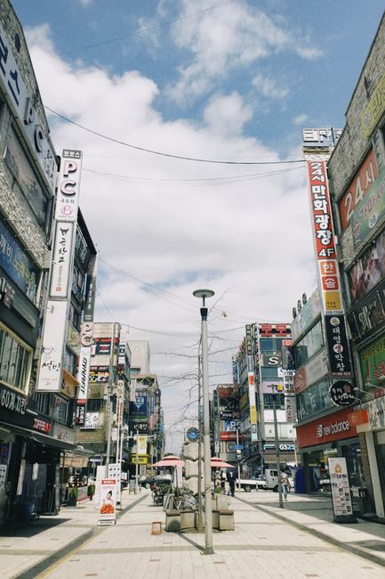 Vibrant city street in South Korea with colorful signs and busy urban atmosphere under a clear sky.