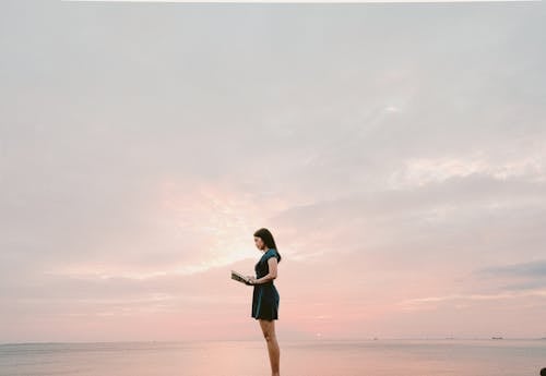 女人穿著黑裙子站和看書