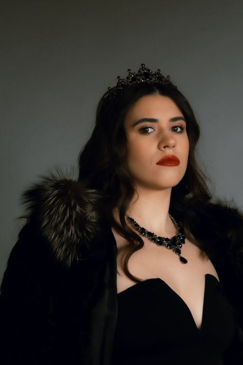 Free Sophisticated portrait of a woman wearing a crown and necklace in a studio setting. Stock Photo