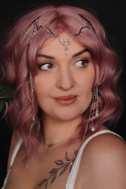A woman with pink hair wearing a headpiece