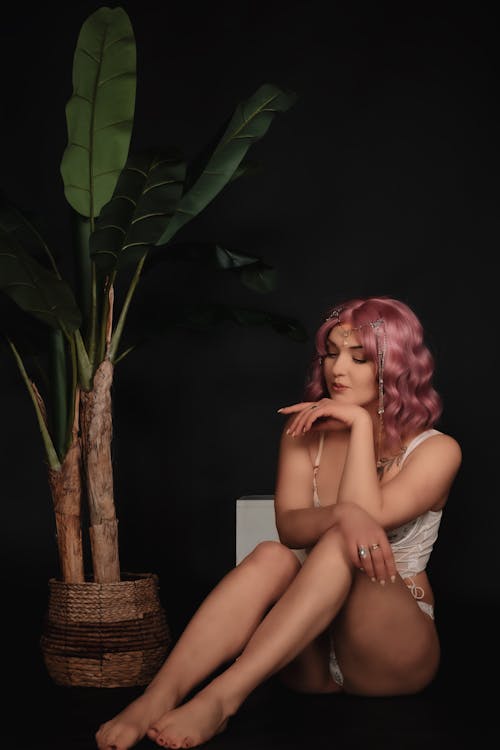 A woman with pink hair sitting on a chair