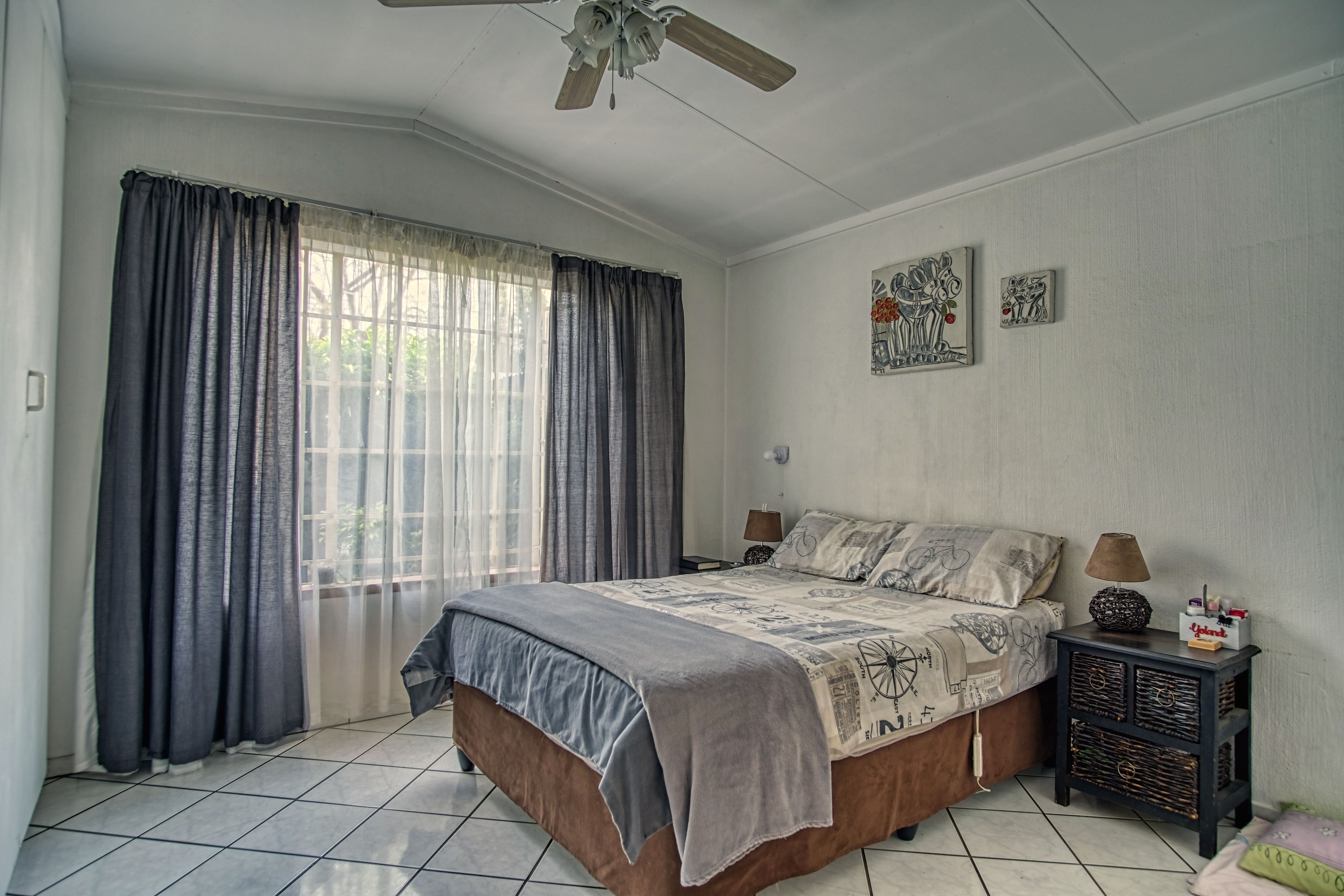 A bedroom with a bed, a ceiling fan and a window