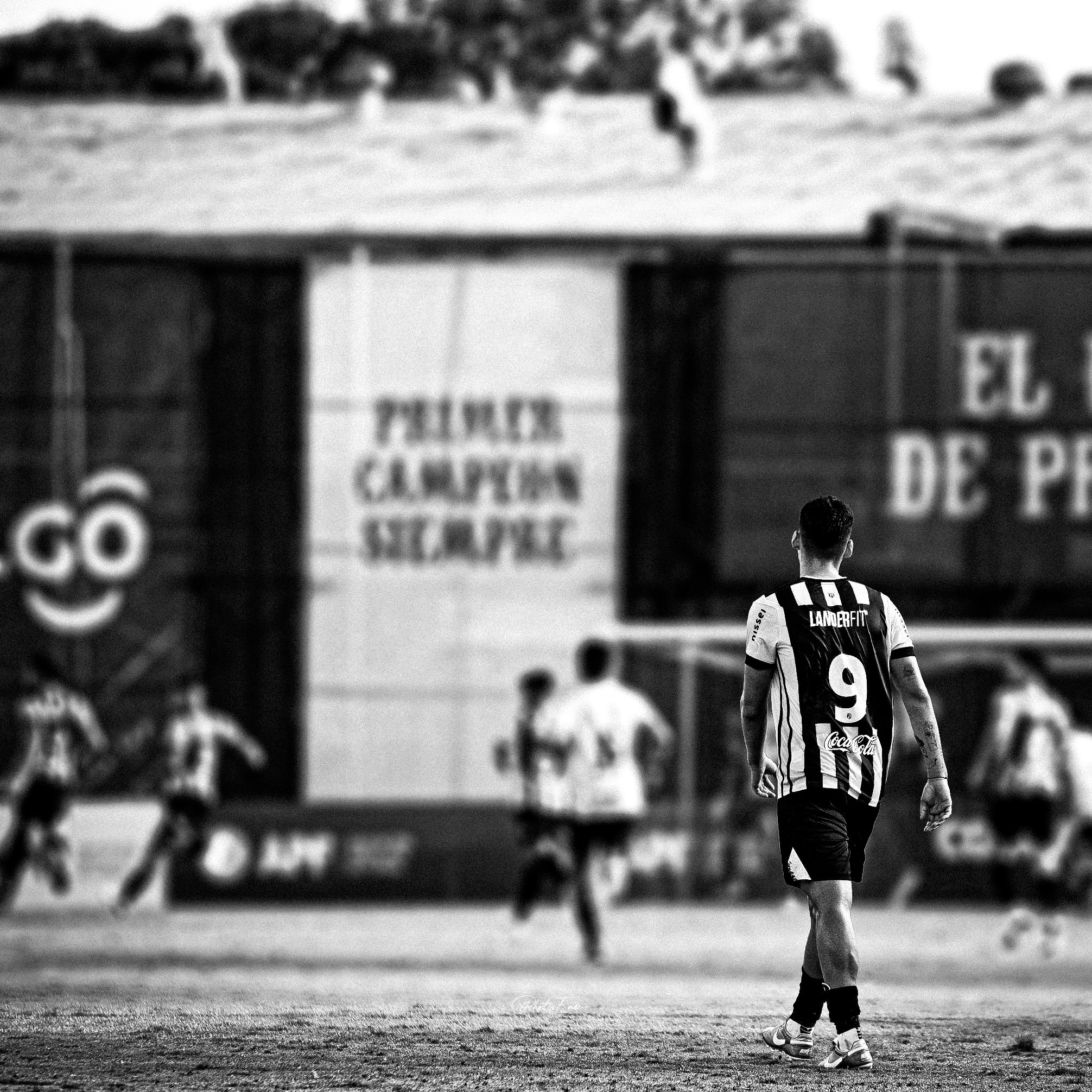 A black and white image of a soccer player in sportswear on Asunción field.