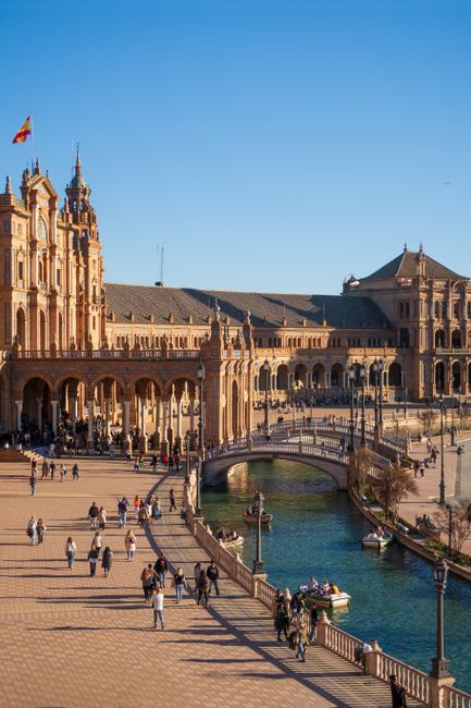 Tourists walking at Plaza de España in Seville, showcasing stunning architecture.