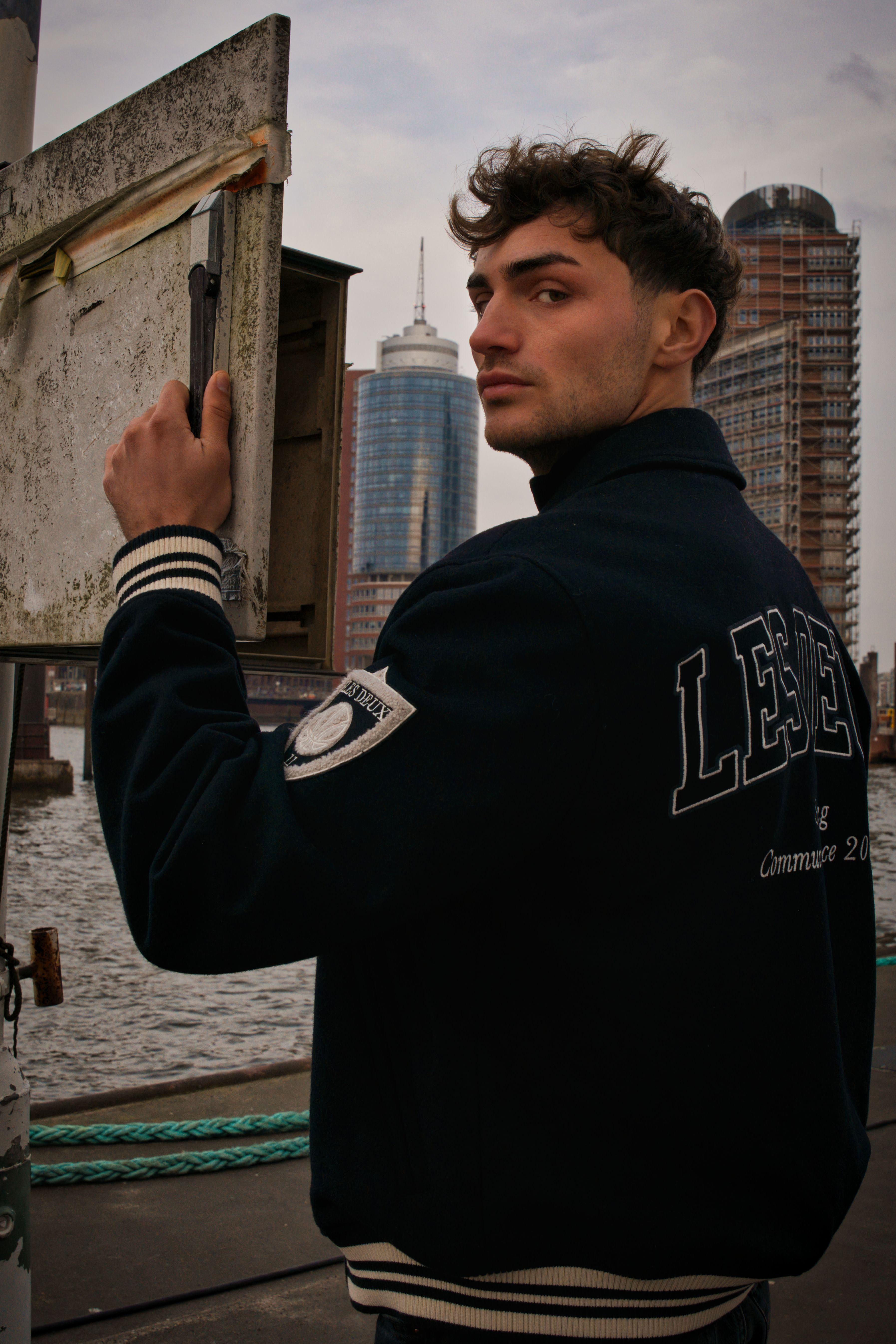 Portrait of a young man standing near a harbor in Hamburg, Germany.