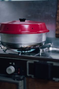 Close-up of a red lidded pot on a gas stove, ideal for cooking and kitchen themes.