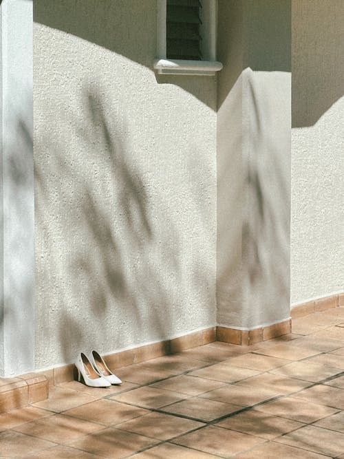 A white shoe on the ground next to a wall
