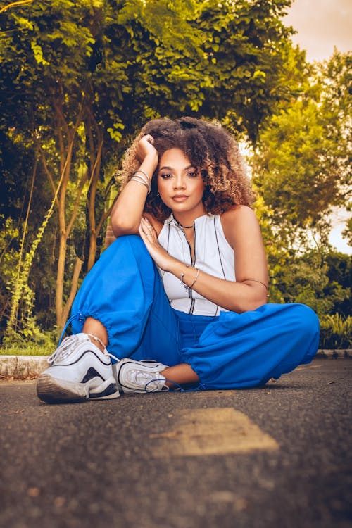 A woman sitting on the ground in blue pants and sneakers