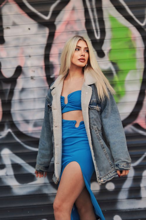 A blonde woman in a blue dress and denim jacket