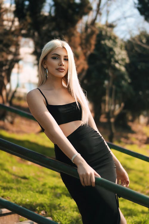 A blonde woman in a black dress is posing for a photo