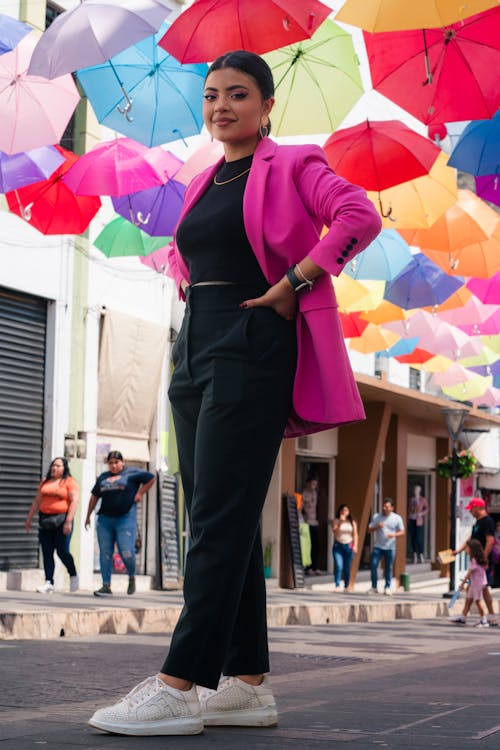 A woman standing in the middle of a street with colorful umbrellas