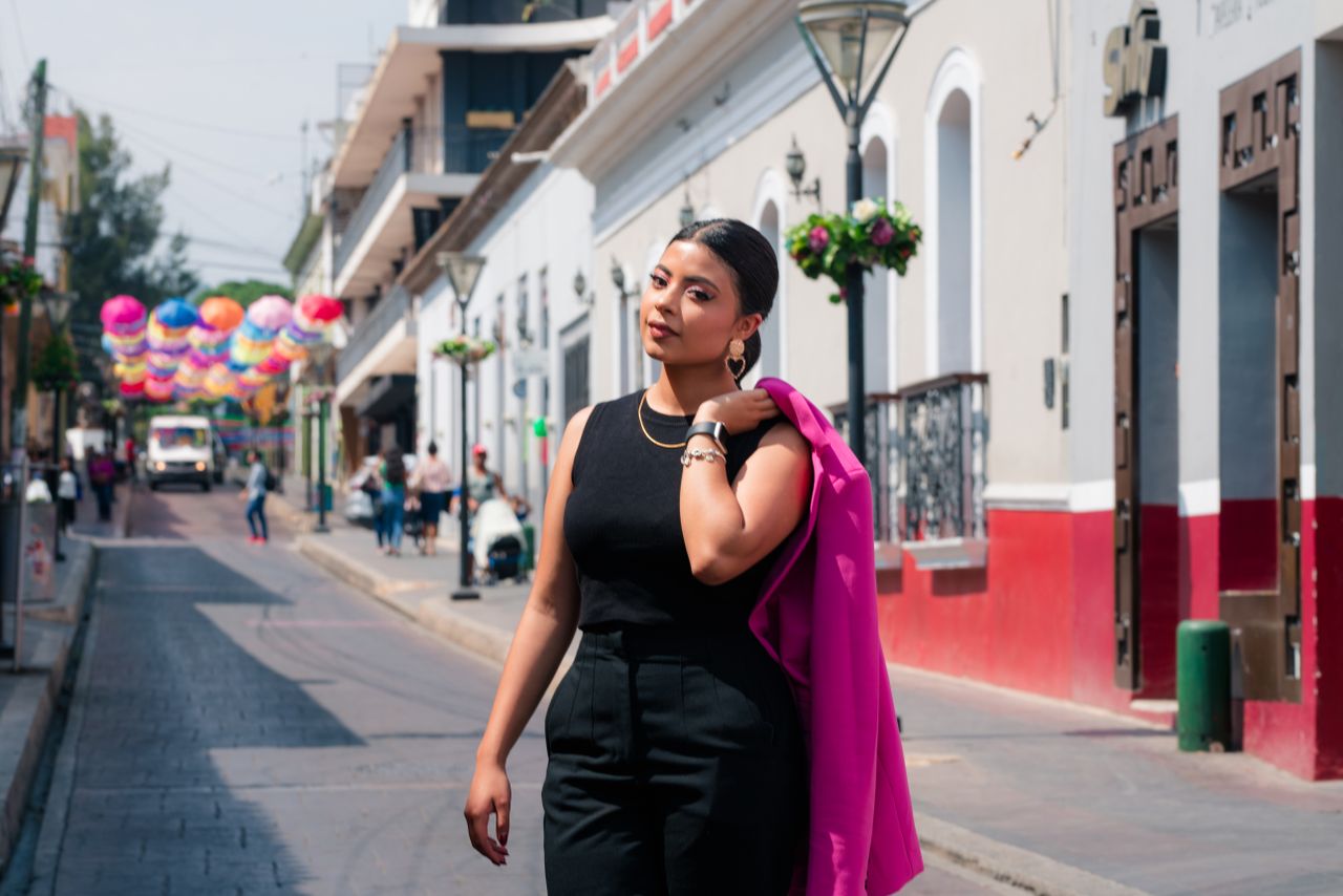 elegant woman in a pink jacket walking down a vibrant street with colo