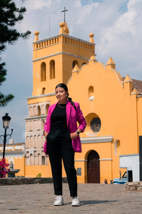 Woman in Pink Suit Jacket Standing with Church Building behind