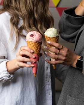 Two women holding cones with pink and green ice cream, showcasing accessories.