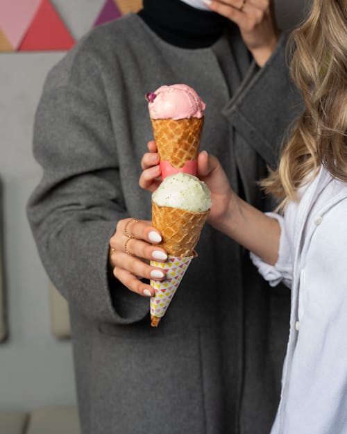 Two women holding ice cream cones in front of them