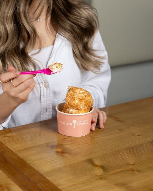 A woman eating ice cream with a pink spoon