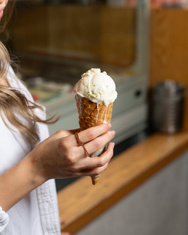 A woman holding an ice cream cone in front of a window