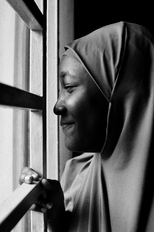 A woman in a hijab looking out a window
