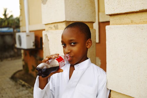 A young boy drinking a soda from a bottle