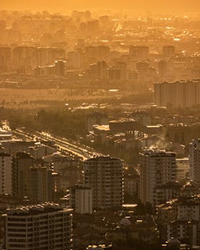 A dramatic aerial view of Kayseri, Türkiye during sunset, showcasing tall buildings and a vibrant cityscape.