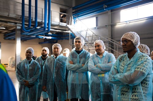 A group of people in blue coats standing in a factory