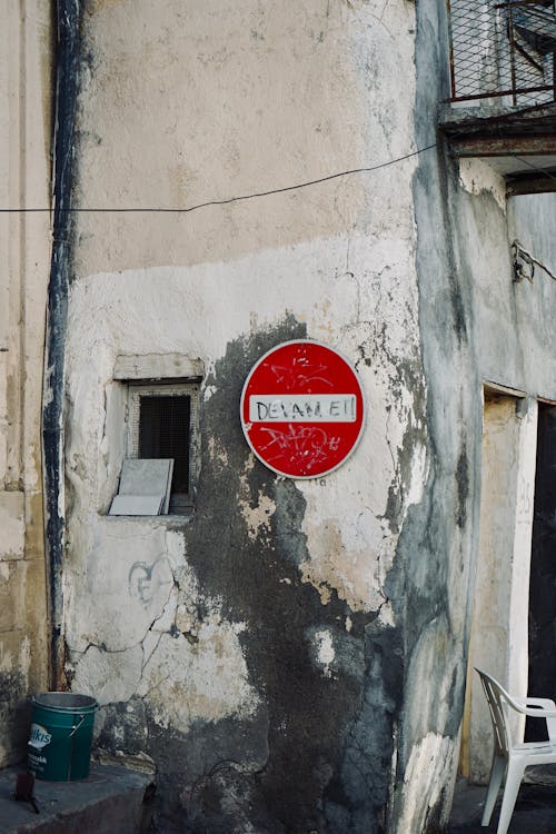 A red stop sign on a wall next to a building