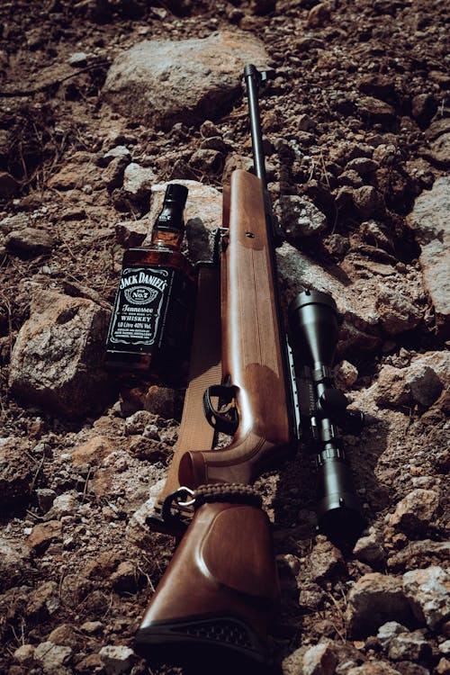 A rifle and bottle of whiskey on the ground