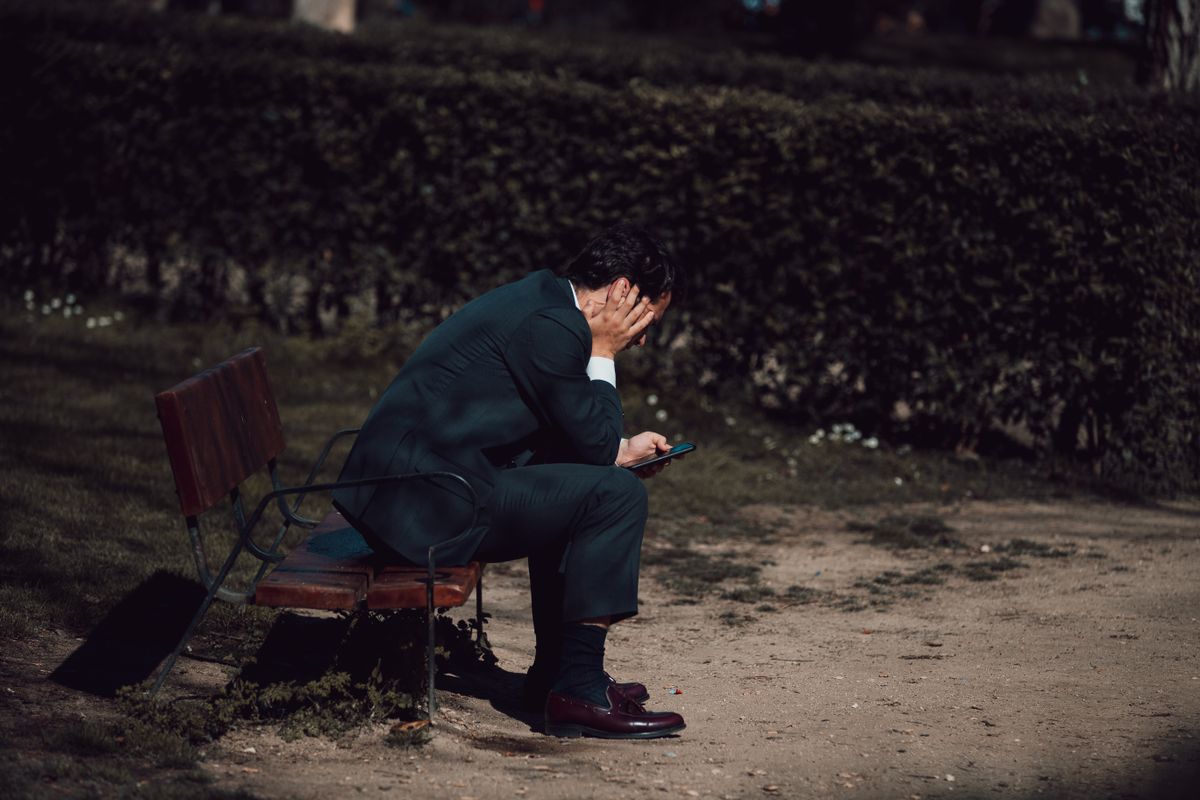 Worried man checking his smartphone outdoors