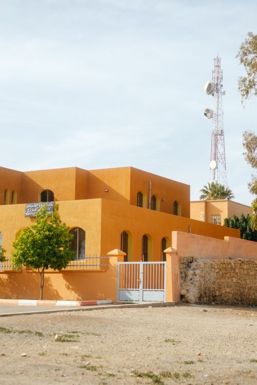 Free Vibrant orange building with a distinct white gate and telecom tower in the background. Stock Photo