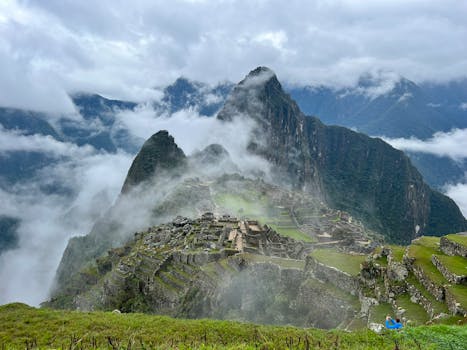 Breathtaking view of Machu Picchu shrouded in clouds, showcasing its ancient ruins in the Andes mountains.